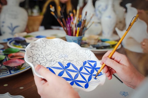 Close up of resident painting a ceramic piece